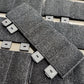 Close-up of textured gray tiles with square cutouts on a light background