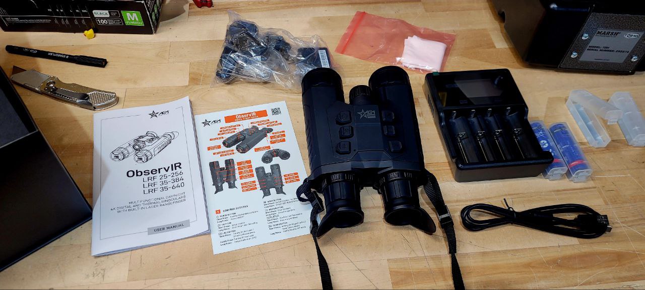 Binoculars with accessories and manuals on a wooden table