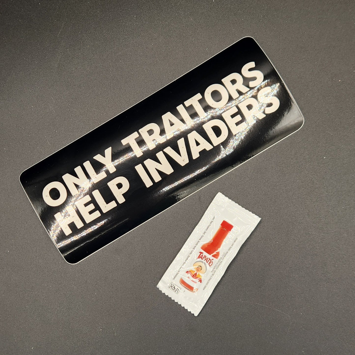 Two stickers on a dark surface, one black and white, the other red and white.