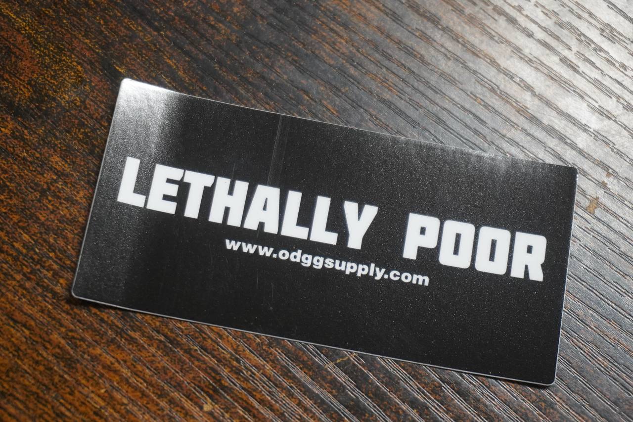 Black card with 'LETHALLY POOR' text on a wooden surface
