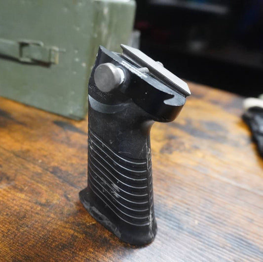 Black gun grip on a wooden surface with a blurred background