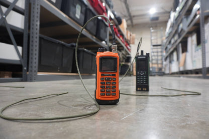 Orange handheld device with a cable on a warehouse floor