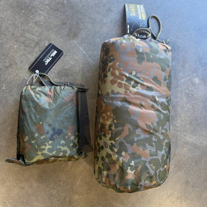Two camouflage sleeping bags on a gray surface with tags attached.