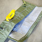 Green tool bag with a yellow tool on a concrete floor