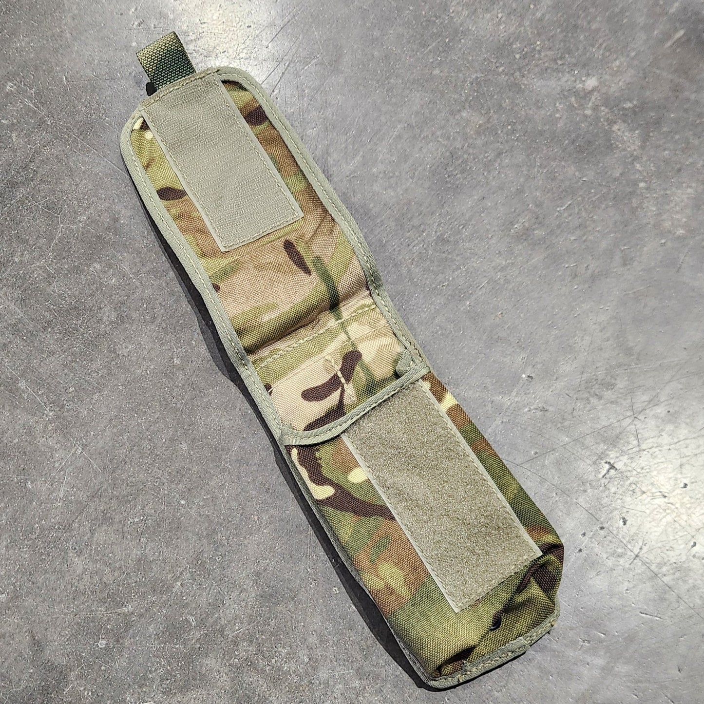 Multicam-patterned pouch on a gray concrete surface
