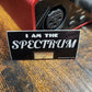 Sticker with 'I am the Spectre' text on a wooden surface