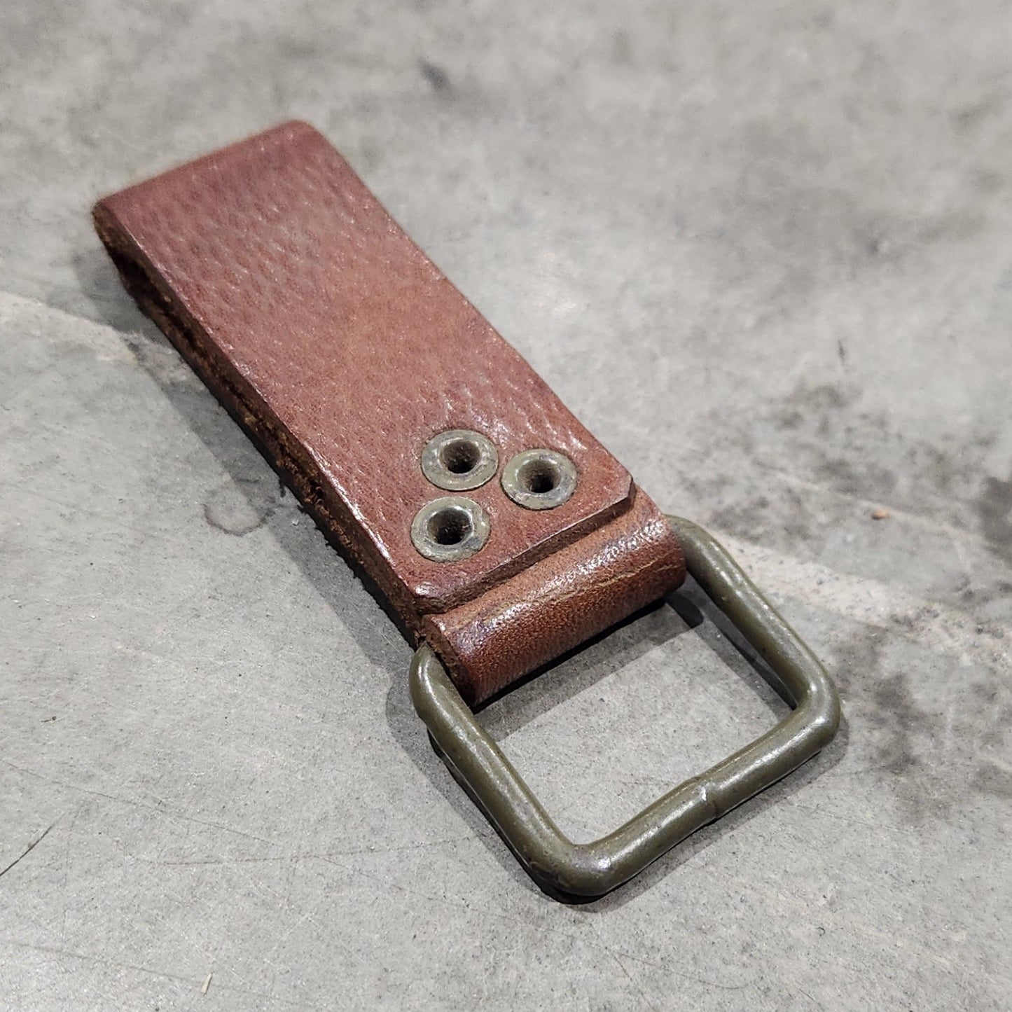 Brown leather bottle opener on a gray concrete surface
