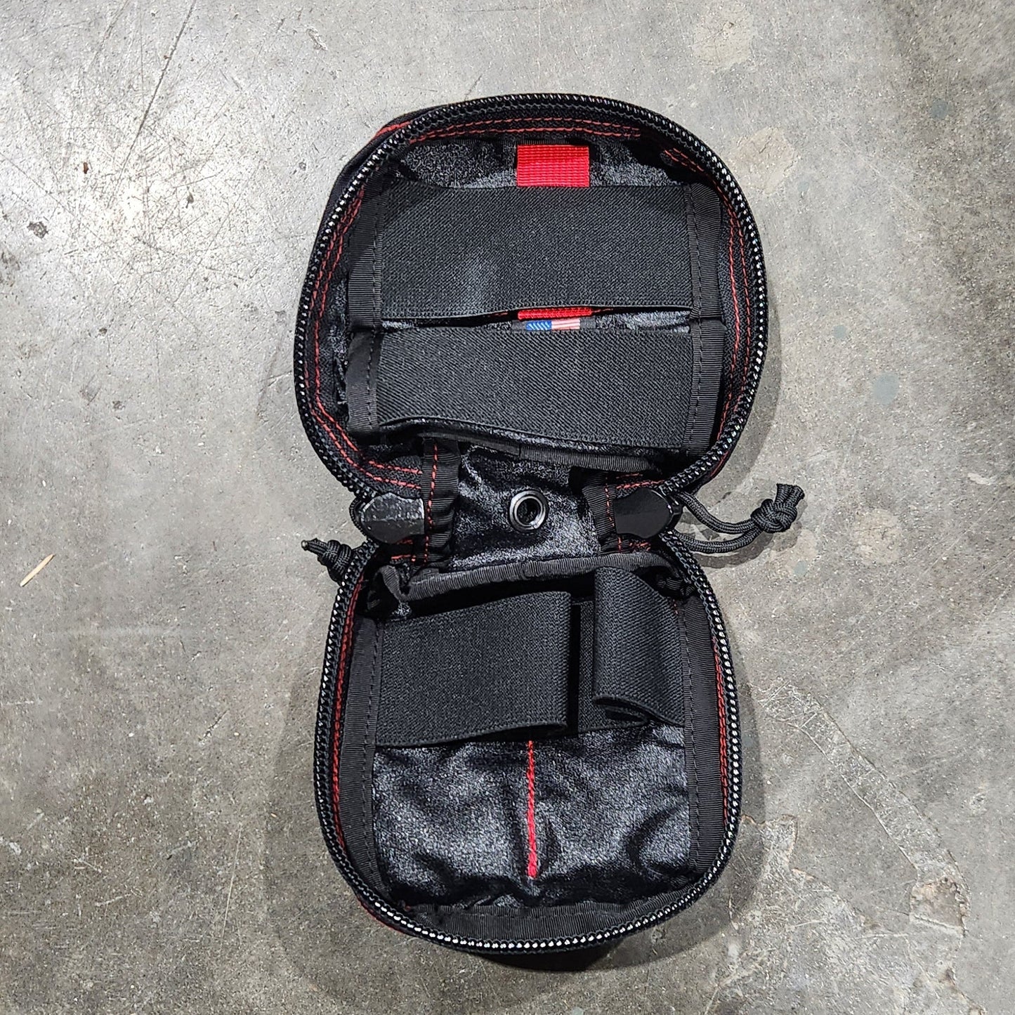 Black travel bag with red accents on a gray concrete surface
