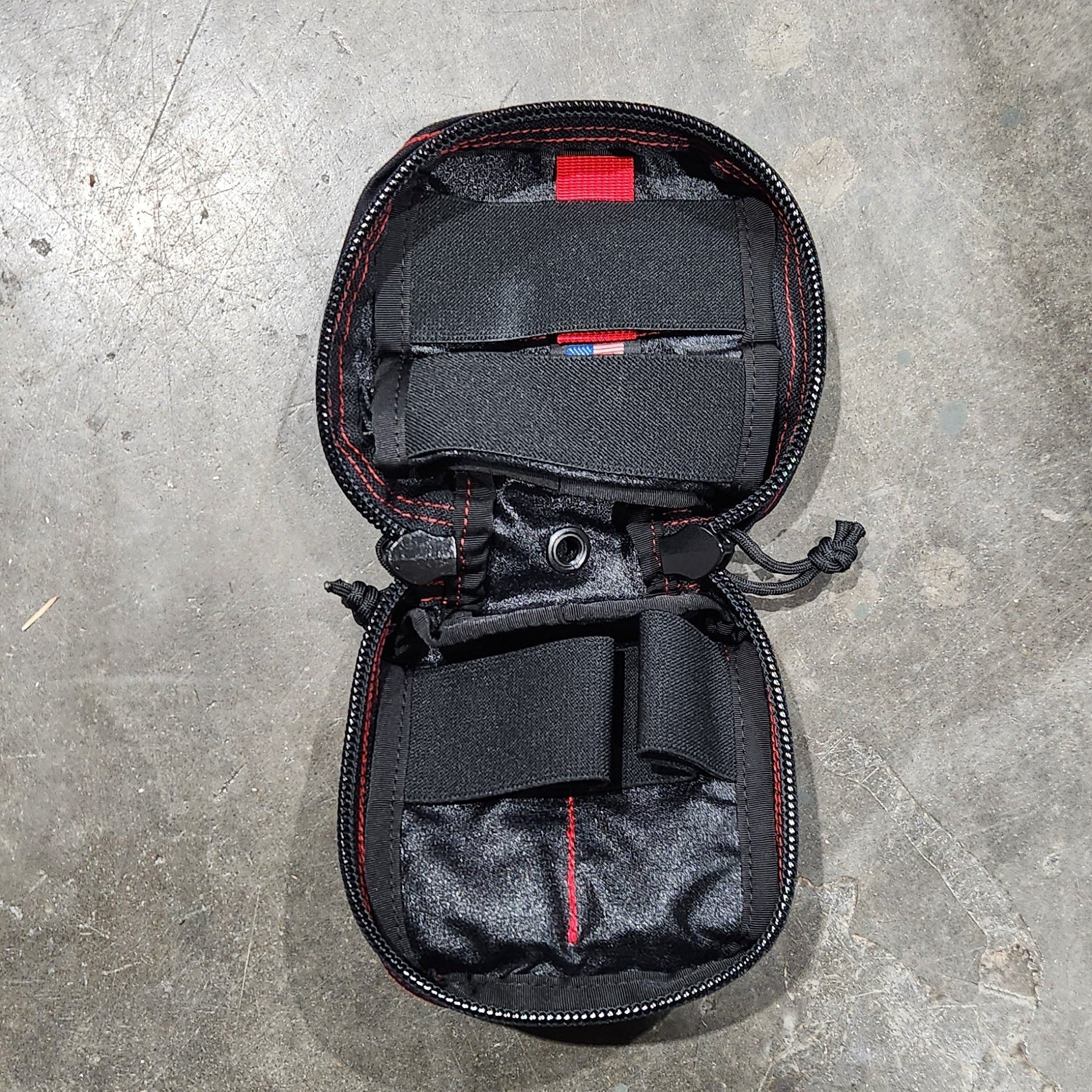 Black travel bag with red accents on a gray concrete surface
