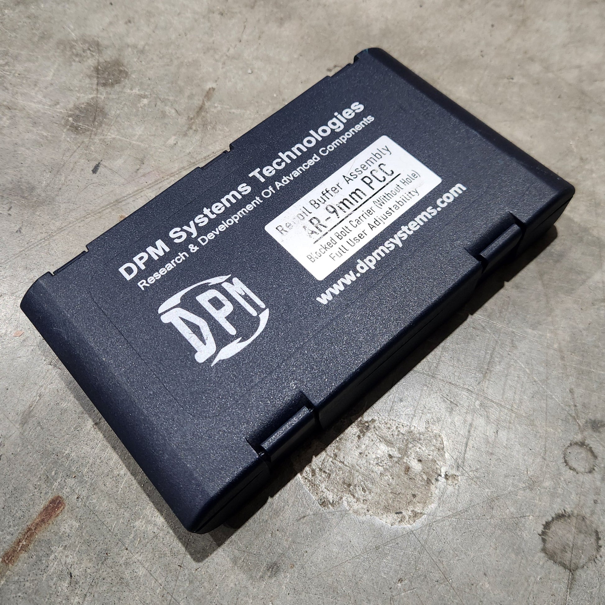 Black battery pack with a label on a concrete surface