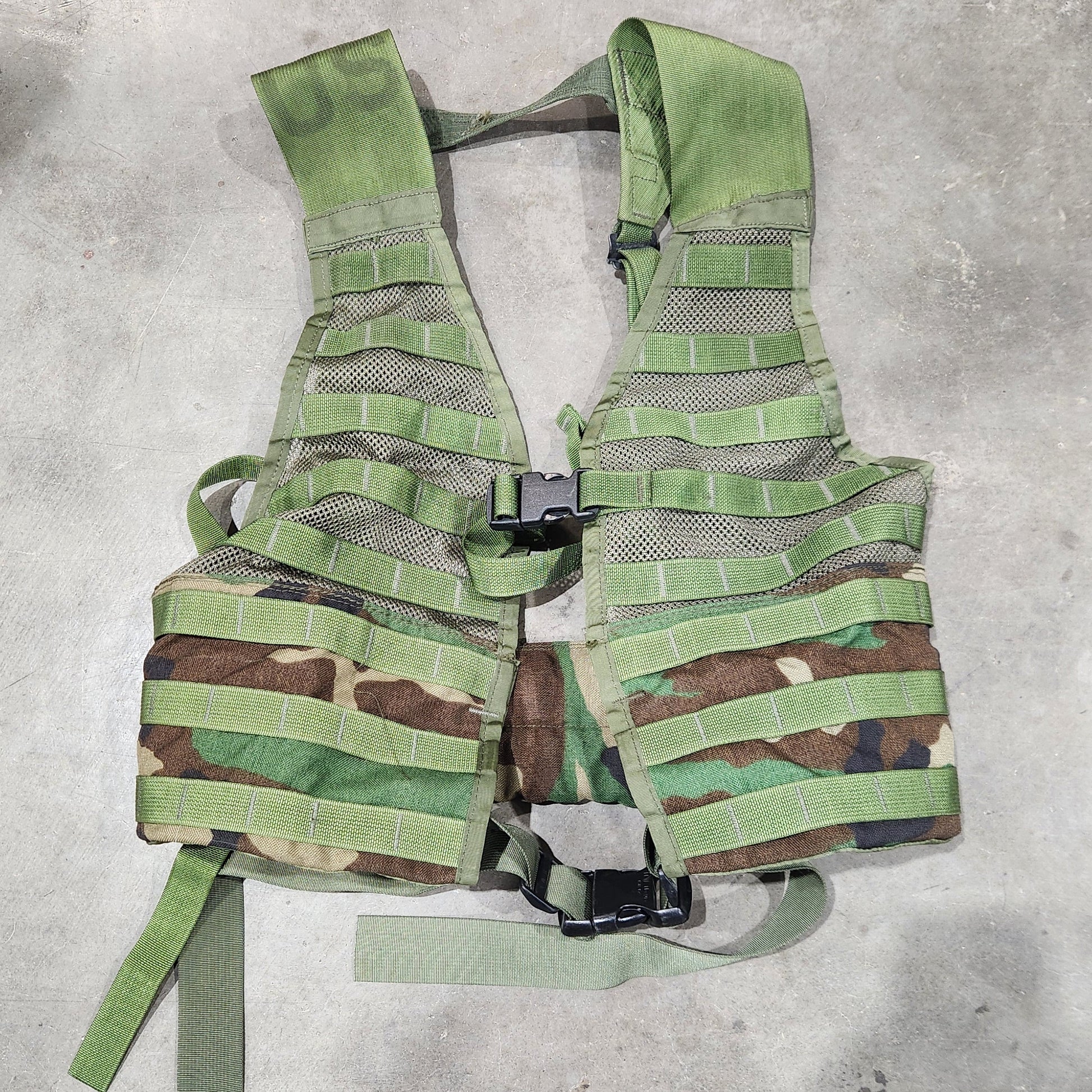 Green camouflage vest on a concrete floor
