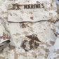 Camouflage military uniform with 'U.S. Marines' text and emblem.