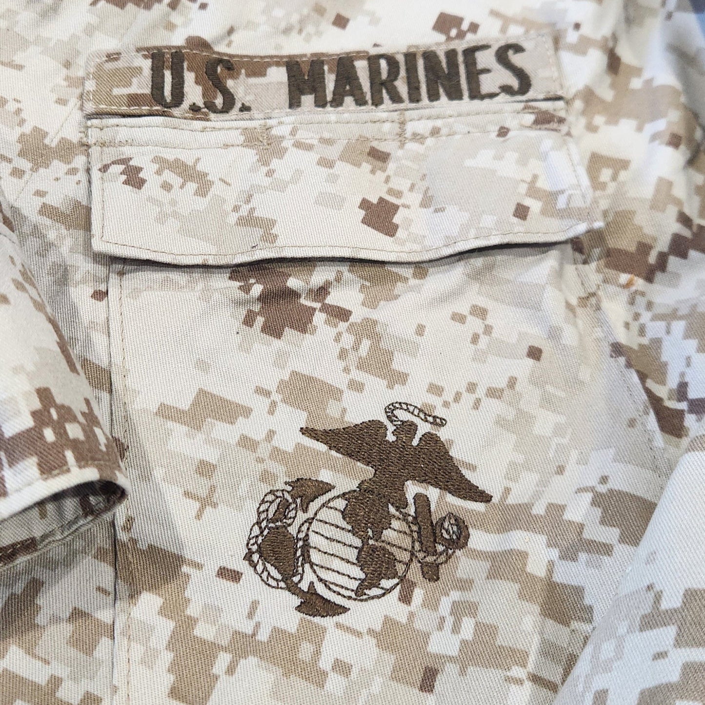 Camouflage military uniform with 'U.S. Marines' text and emblem.