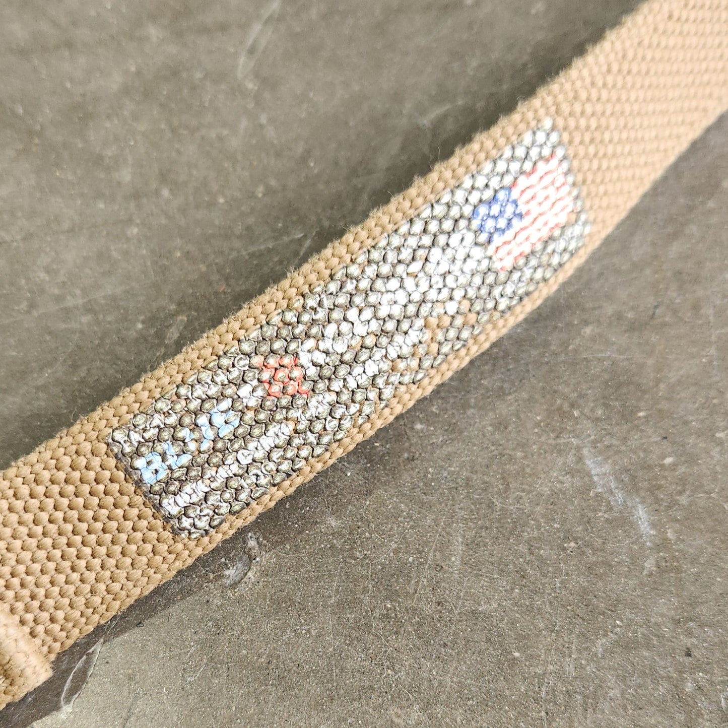 Beige belt with a patterned strap on a gray surface