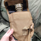 Person holding a tactical gas mask pouch with a gas mask inside, on a green military-style background.