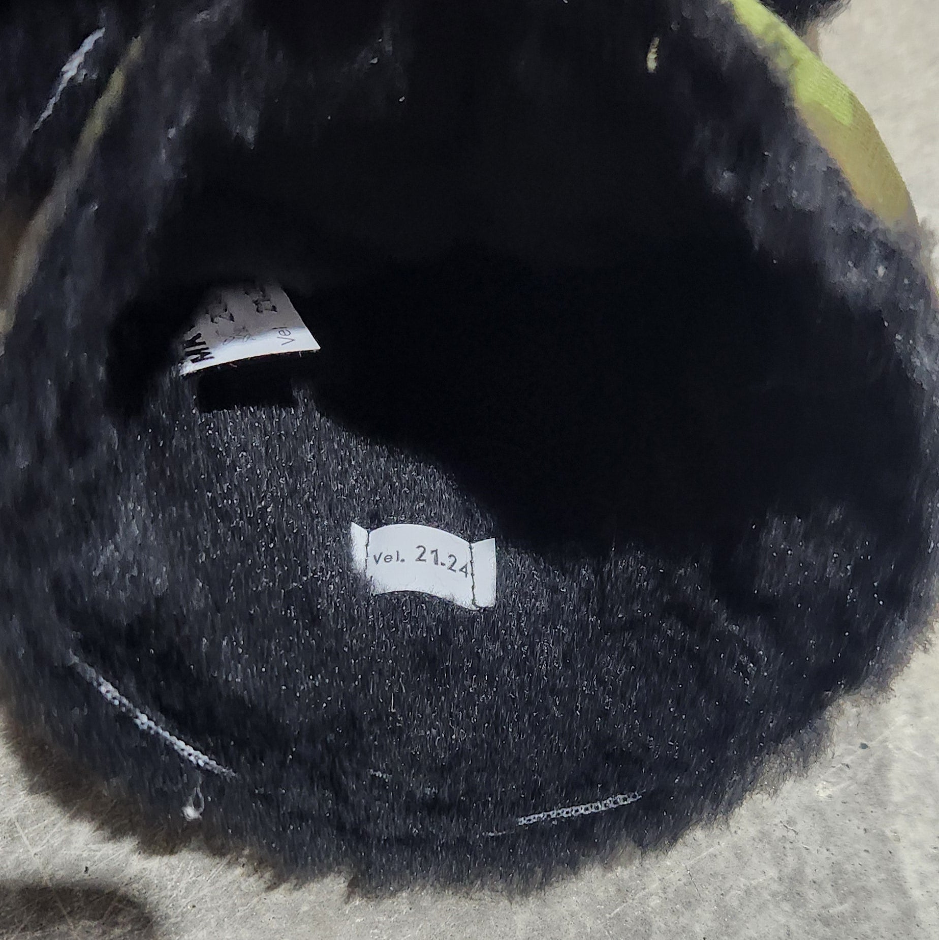 Black fur-lined item held by a hand on a concrete surface