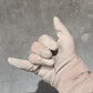 Hand wearing a beige glove pointing on a gray surface