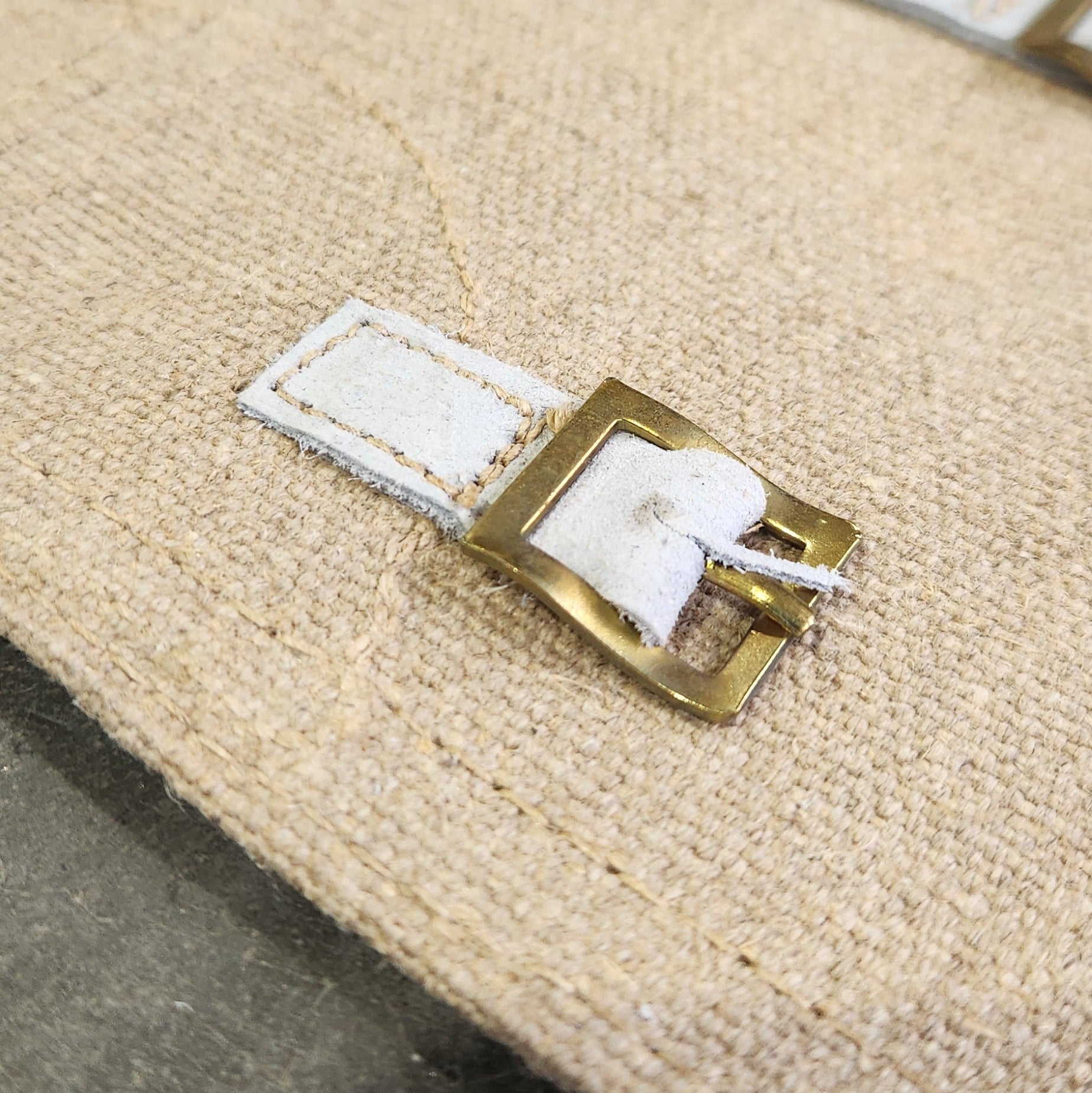 Close-up of a beige fabric with a gold and white tag attached.