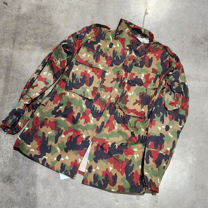 Camouflage-patterned bag on a concrete floor with a shoe visible.