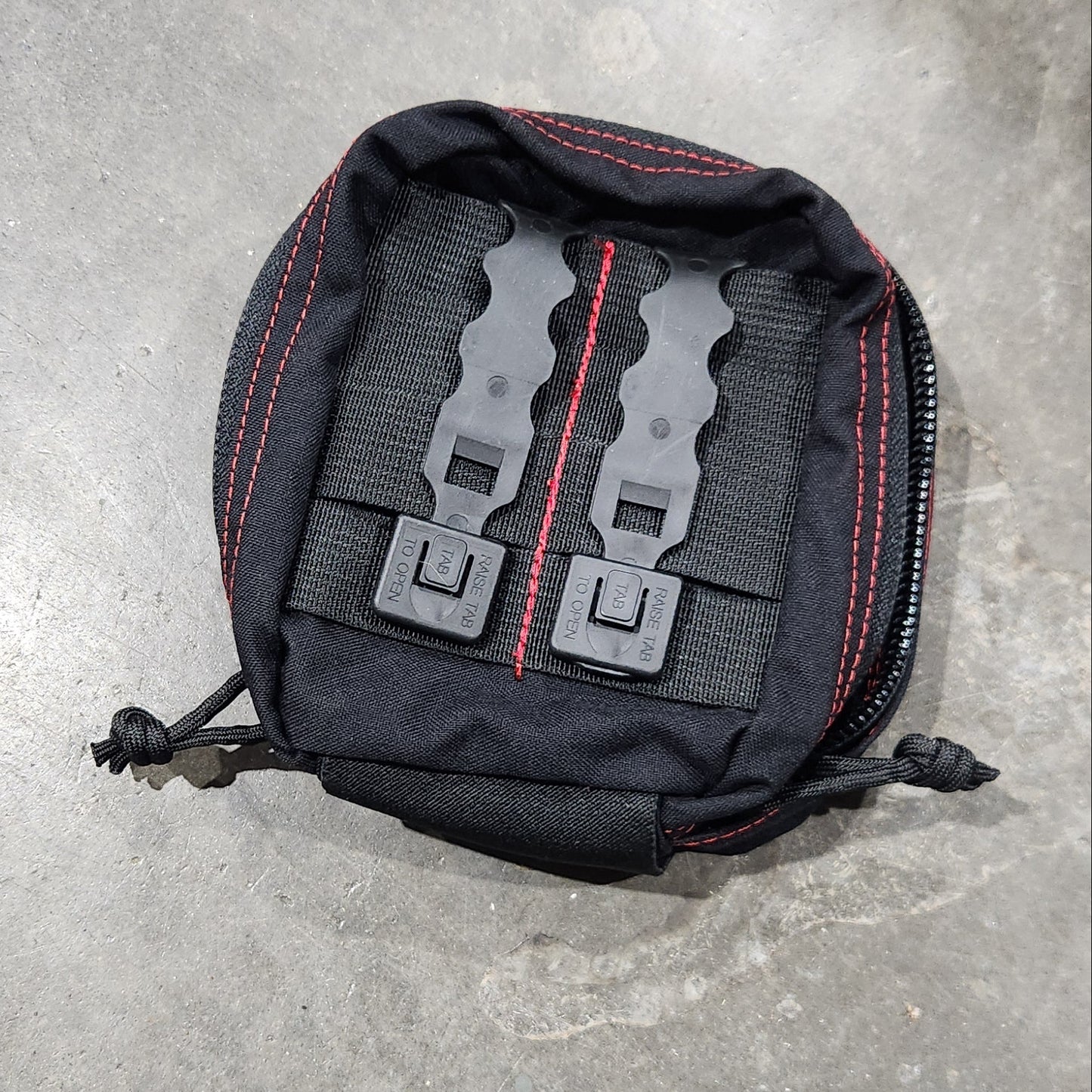 Black tactical pouch with visible branding on a gray concrete surface