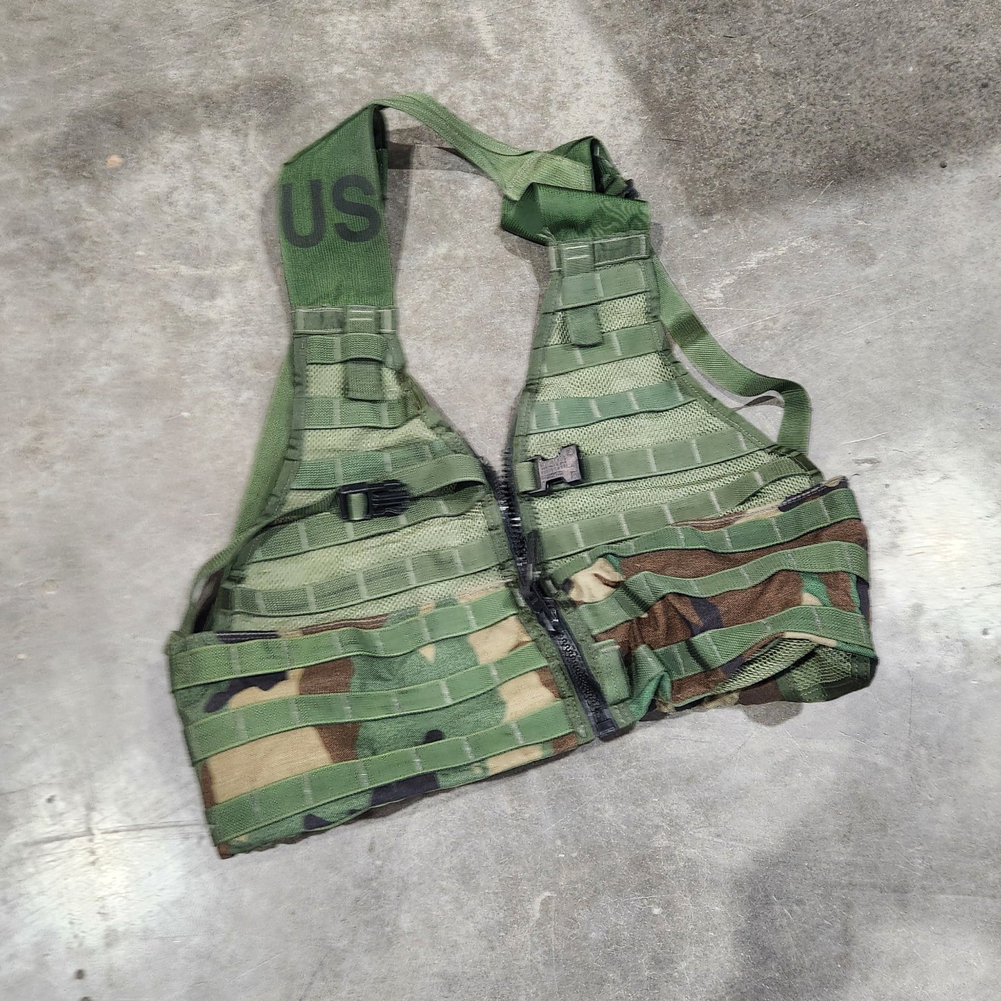 Green military-style vest on a concrete floor