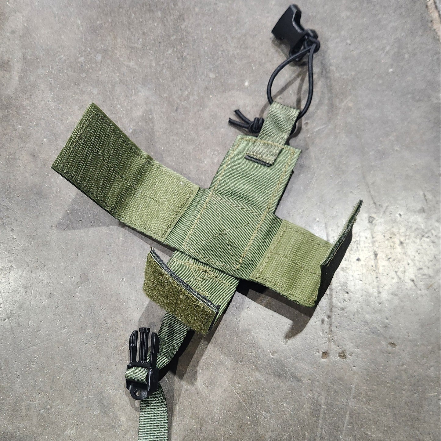 Green tactical pouch on a gray concrete floor