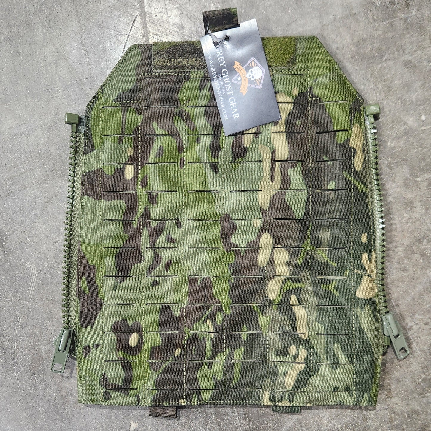 Camouflage pouch on a concrete surface with a visible brand tag.