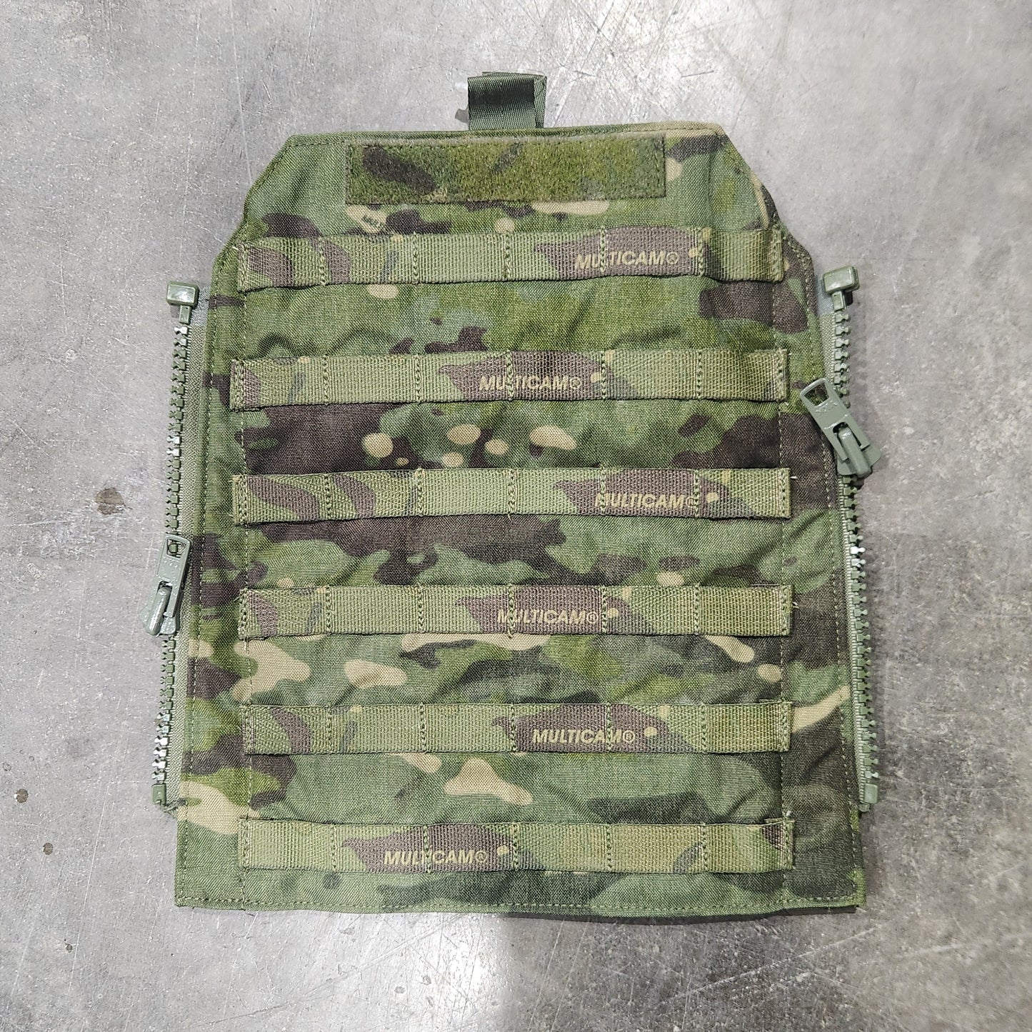 Camouflage-patterned tactical vest on a concrete floor