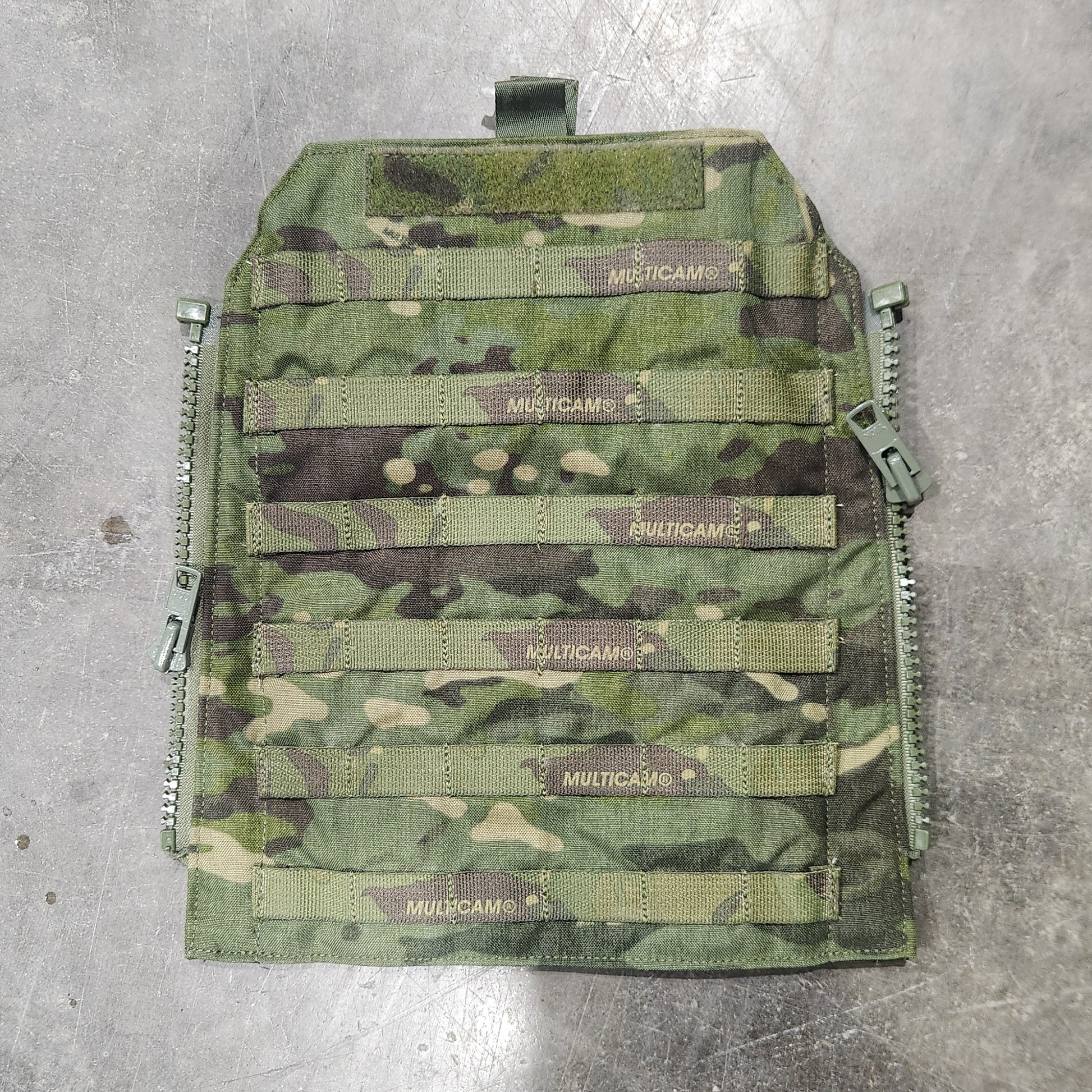 Camouflage-patterned tactical vest on a concrete floor