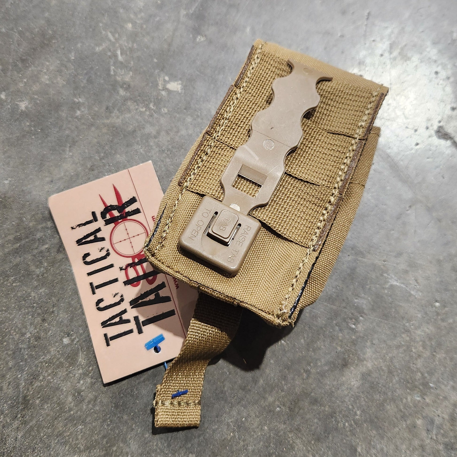 Tan tactical pouch on a metallic surface with a label underneath