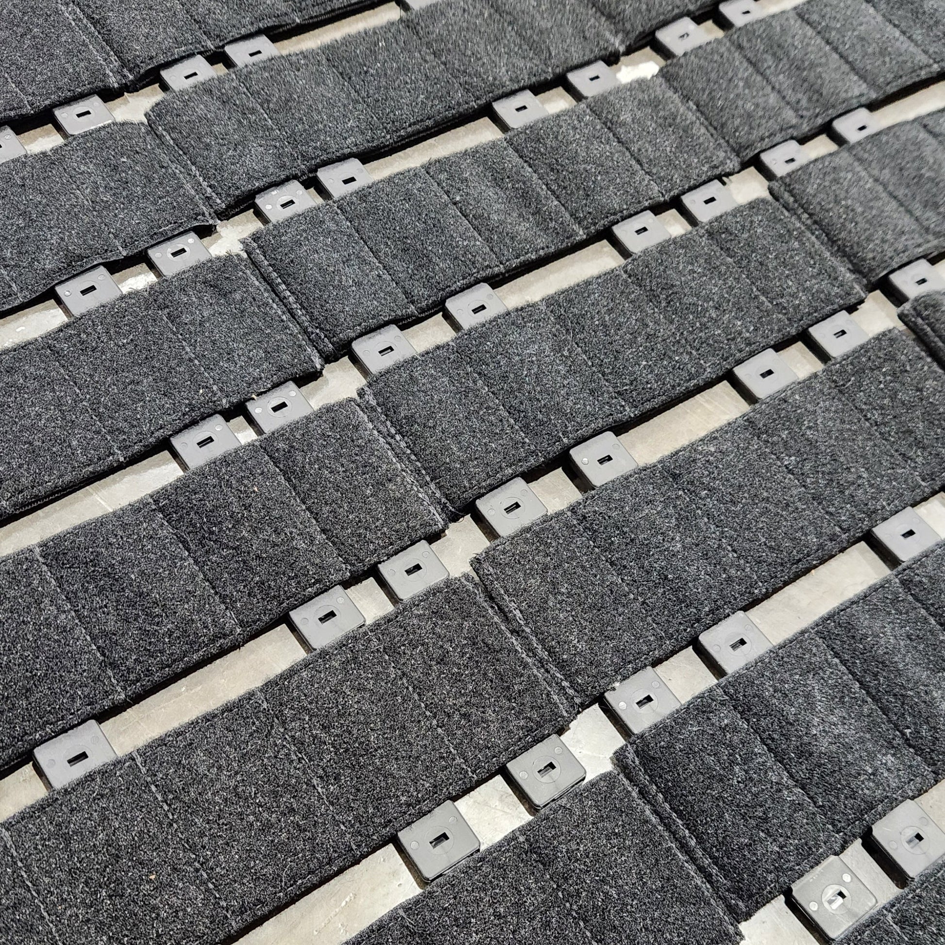 Grid of gray fabric straps with metal hardware on a beige background
