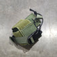 Green tactical pouch on a gray concrete floor