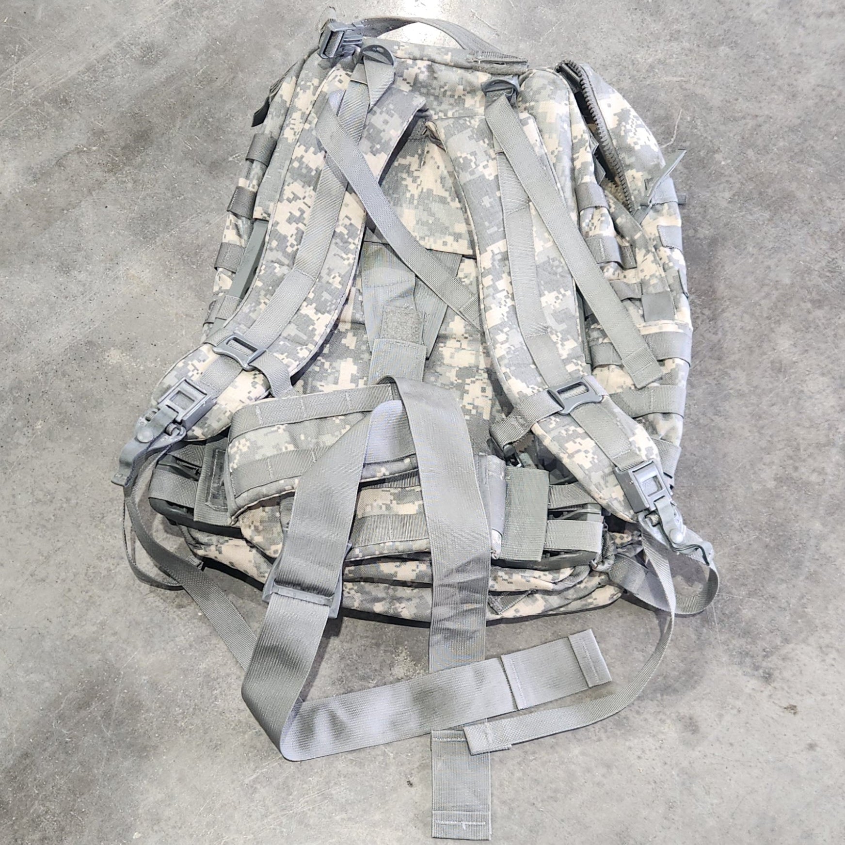 Camouflage backpack on a concrete floor
