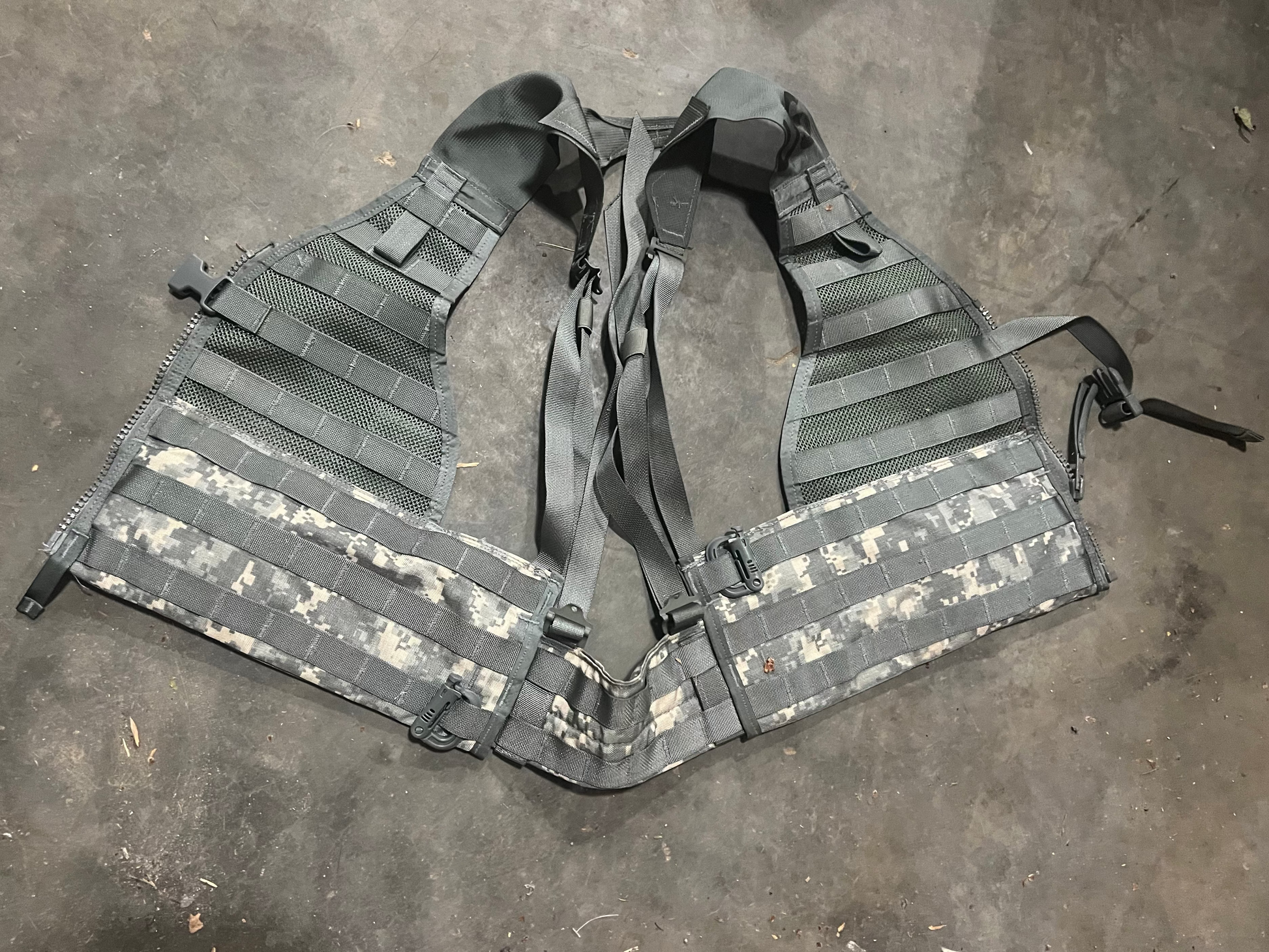 US Military load bearing vest displayed on mannequin, tan in color with multiple pouches and straps.