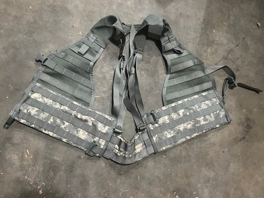 US Military load bearing vest displayed on mannequin, tan in color with multiple pouches and straps.